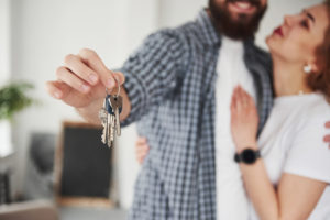 casal feliz com a chave da casa própria após criar um planejamento financeiro