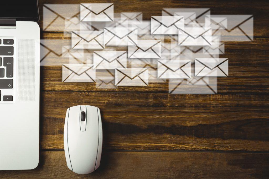 email marketing, um notebook com mouse e vários emails saindo