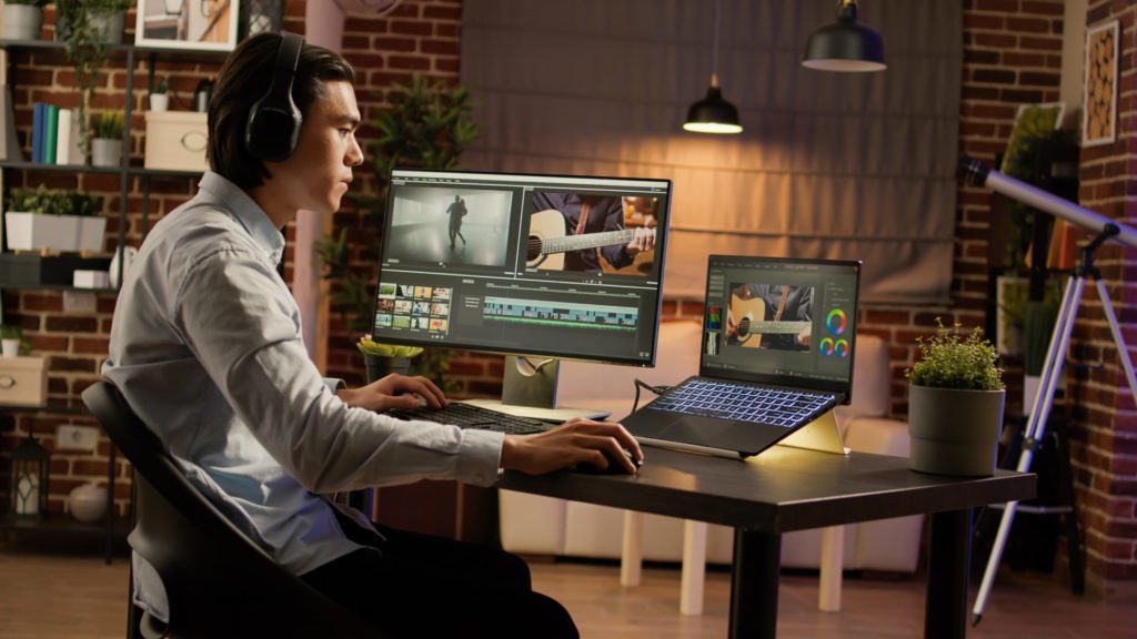 homem editando vídeos no computador e notebook